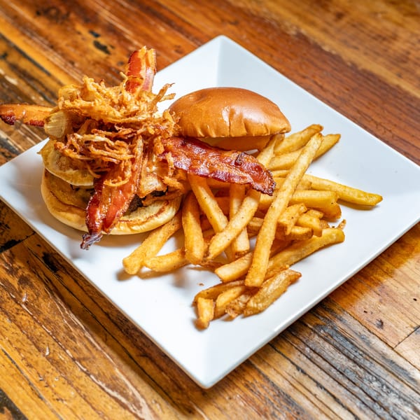 Oy! breakfast burger with crispy fried onions, bacon, and a side of golden french fries.